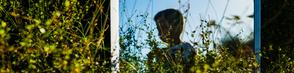 Child in field reflected in a mirror